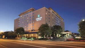 A multi-story hotel with a prominent 'Embassy Suites' sign, featuring a modern design with a flat roof and large windows.