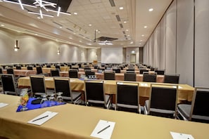 A conference room with rows of tables and chairs, equipped with nameplates and pens.