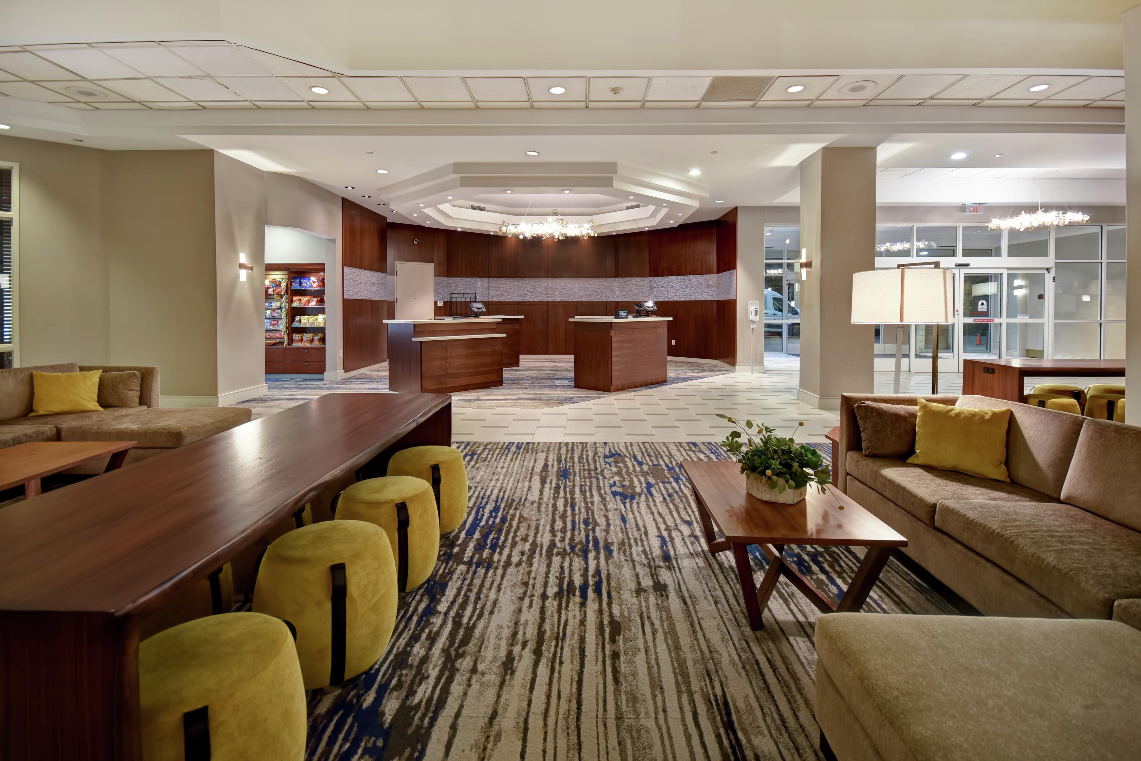 A hotel lobby with a reception desk, seating area, and a large window.