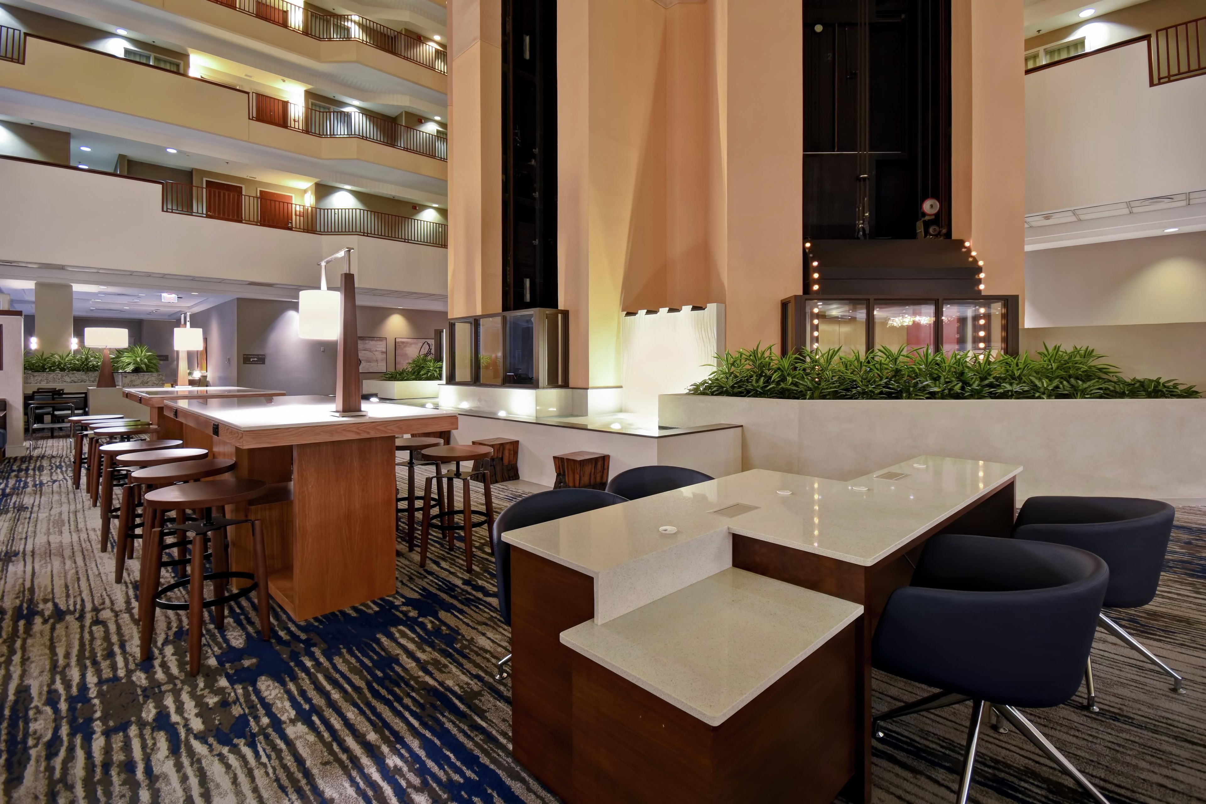A hotel lobby with a reception desk, seating area, and a view of the upper floors.