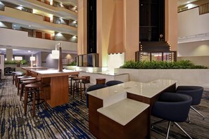 A hotel lobby with a reception desk, seating area, and a view of the upper floors.