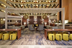 A hotel lobby with multiple seating areas, including sofas and armchairs, arranged around a central coffee table.