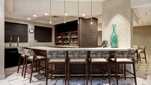 A modern bar area with a high bar counter, multiple stools, and a large decorative vase.