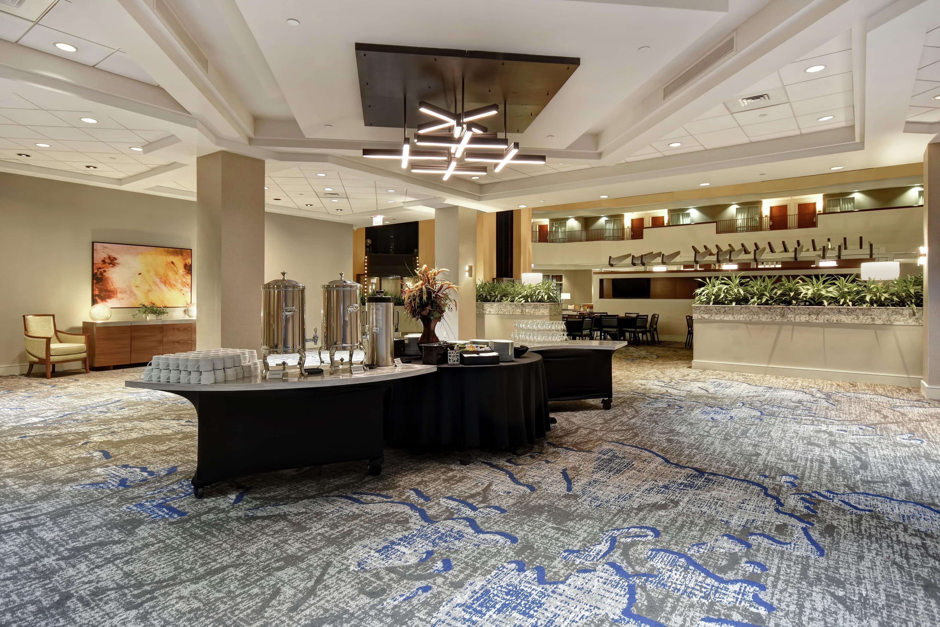 Un hall d’hôtel spacieux avec un coin café, un espace salon et un comptoir d’accueil.