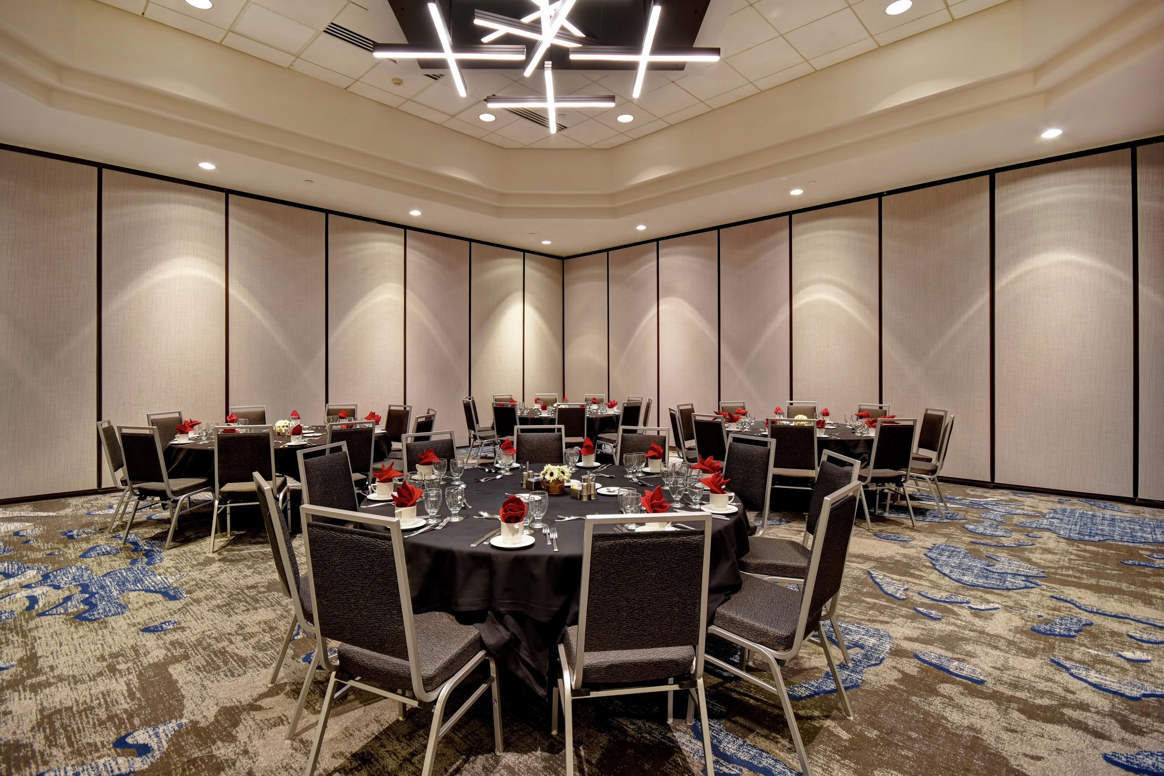 A conference room with round tables, chairs, and a modern ceiling design.
