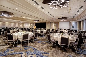 Un amplio salón de banquetes con mesas redondas dispuestas para cenar, equipado con sillas y mantelería.
