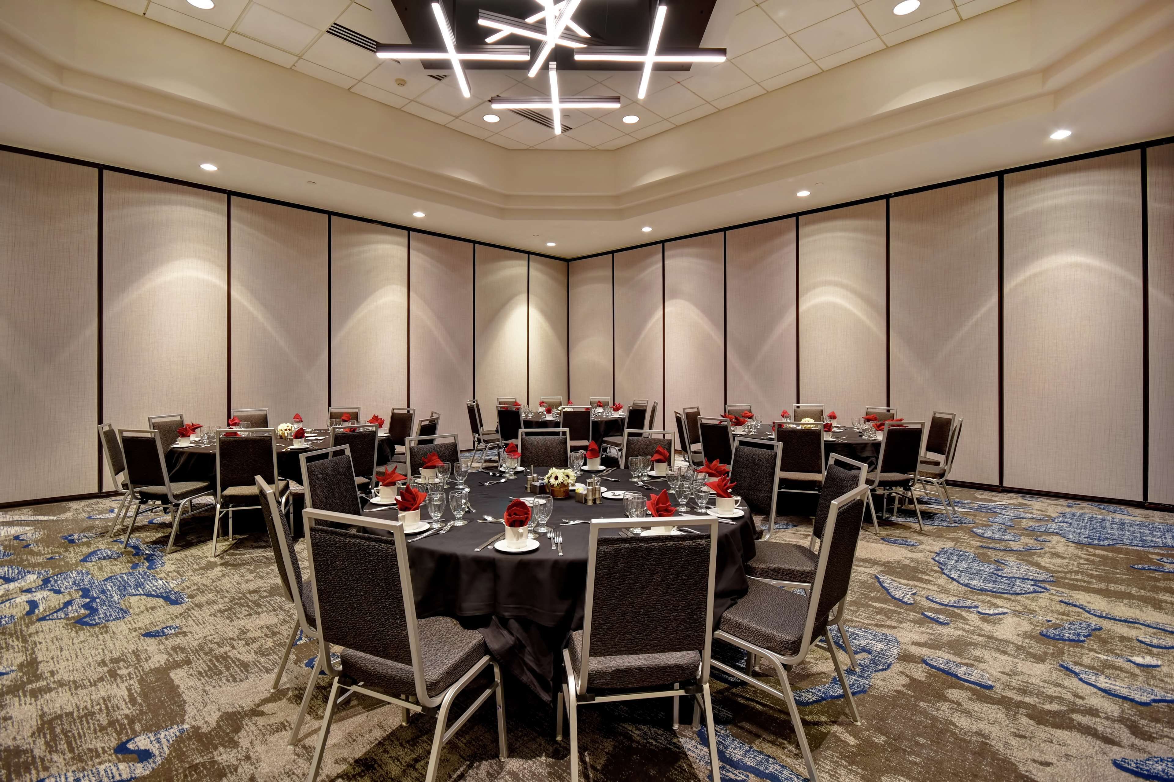 A conference room with round tables, chairs, and a carpeted floor.