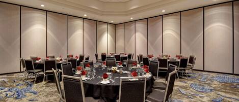 A conference room with round tables, chairs, and a carpeted floor.