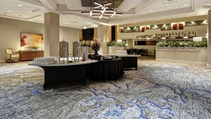 A spacious lobby with a modern chandelier, a reception desk, and a seating area with a patterned carpet.