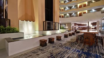 A hotel lobby with a reception desk, seating area, and a staircase leading to upper floors.