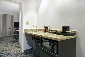 A compact hotel kitchenette with a built-in coffee maker, a microwave, and a sink.