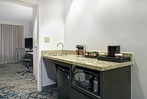 A compact hotel kitchenette with a built-in coffee maker, a microwave, and a sink.