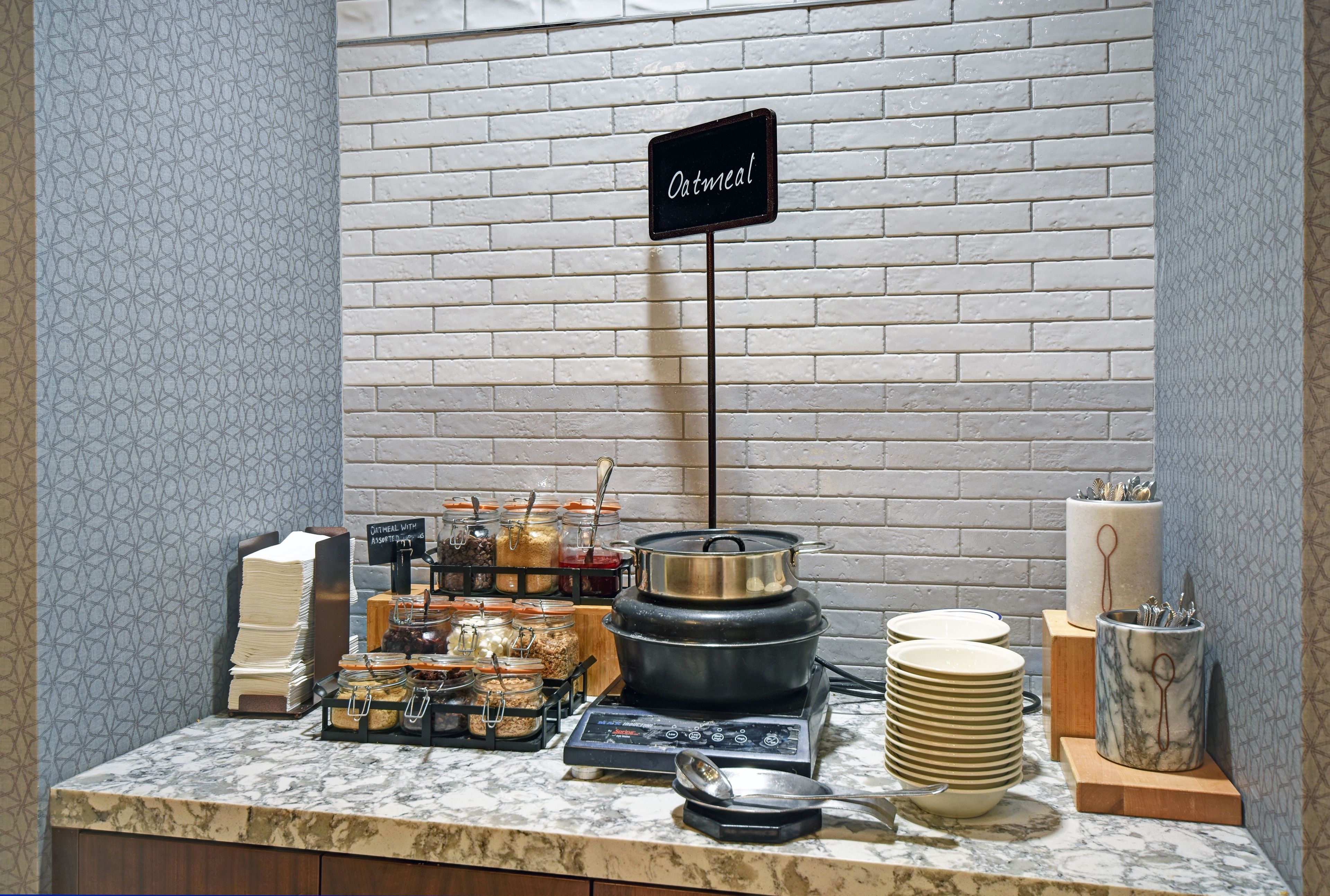 Un buffet de petit-déjeuner proposant divers plats, un panneau indiquant « porridge » et un mur décoré d’un motif marbré.