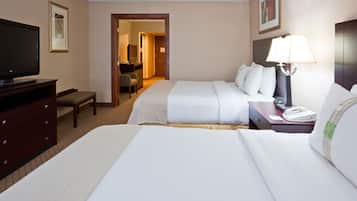A hotel room with two beds, a TV, a desk, and a lamp.
