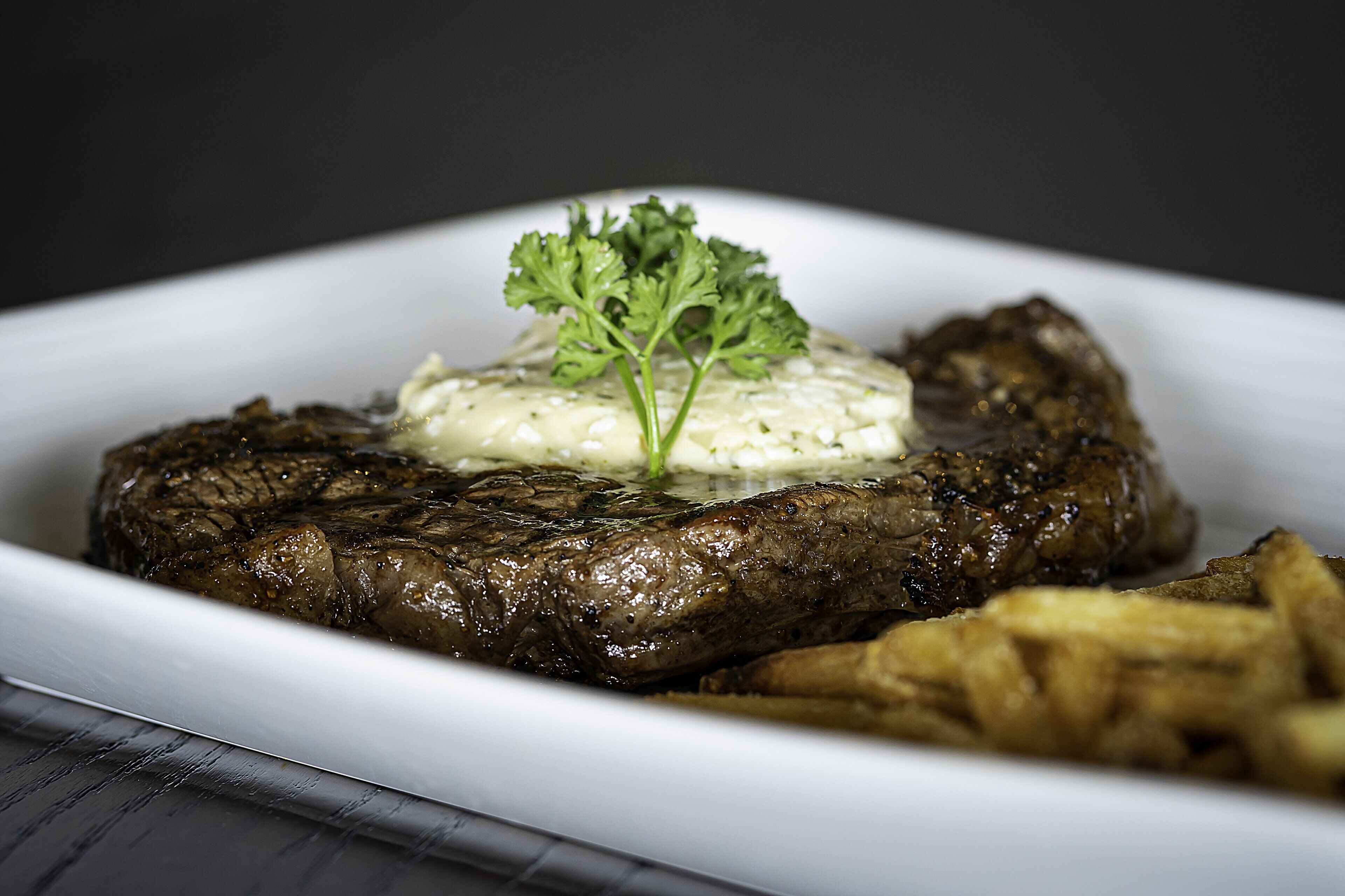 A plate with a steak, a dollop of sauce, and a garnish.