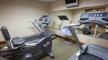 A fitness room with treadmills and a mirrored wall.