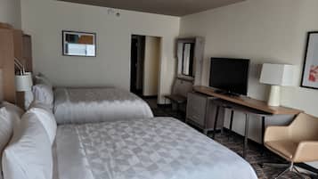 A hotel room with two beds, a desk with a TV, a chair, and a dresser.