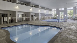 Una piscina interna con diversi livelli di balconi, ringhiere bianche e pavimento in pietra.