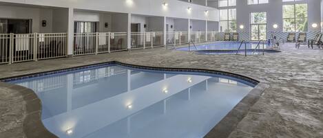 Una piscina interior con varios niveles de balcones, barandillas blancas y suelo de piedra.