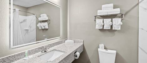 A bathroom with a granite sink, a toilet, a towel rack, and a mirror.