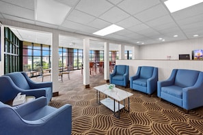 A spacious lobby with blue armchairs, a coffee table, and a reception desk.