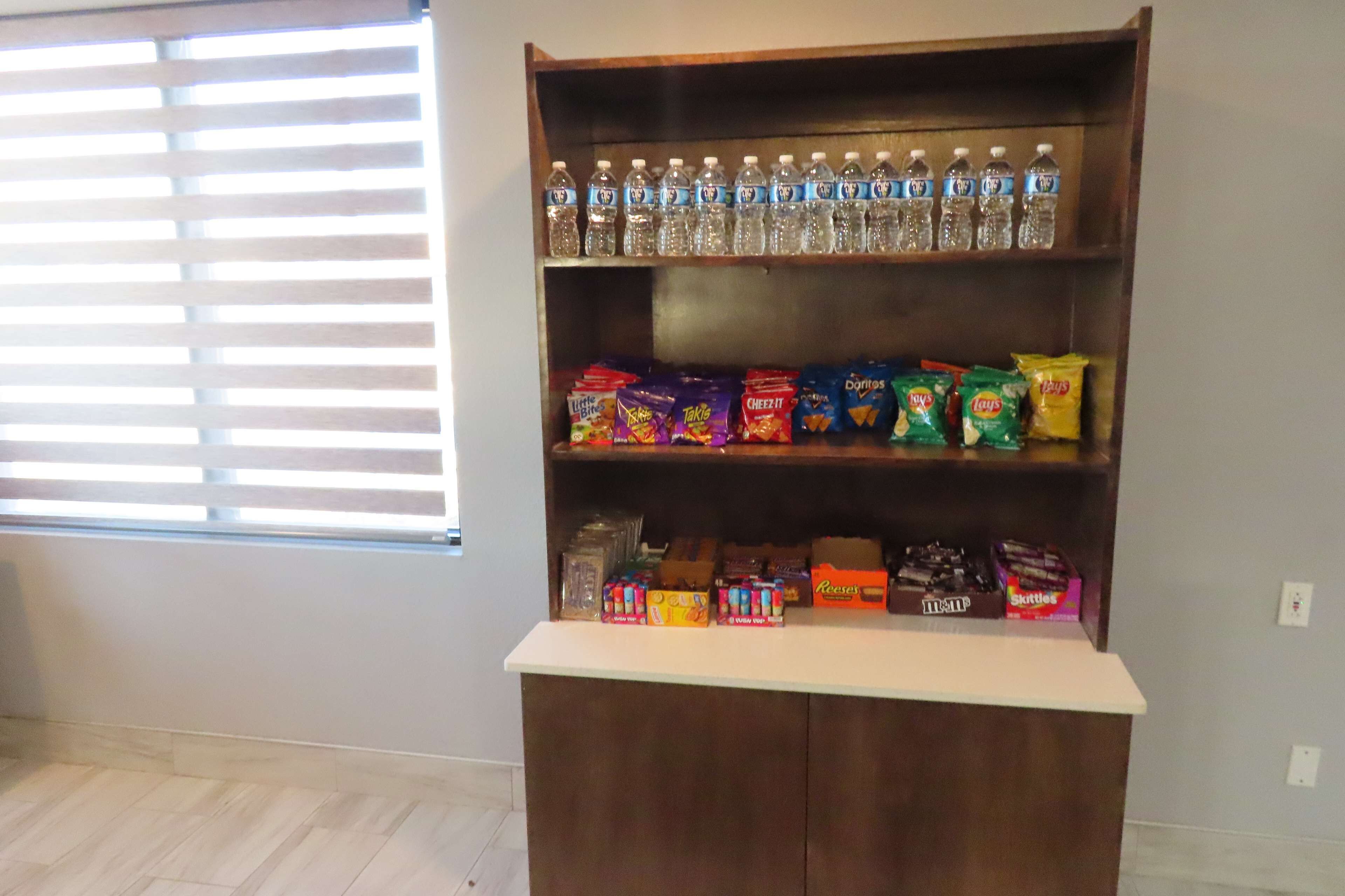 Una estantería con agua embotellada, bolsas de aperitivos y dulces.