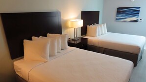A hotel room with two beds, a nightstand with a lamp, and a painting on the wall.