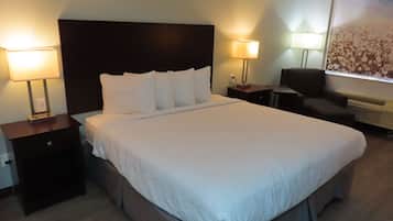 A hotel room with a large bed, two bedside lamps, a chair, and a large window with a view.