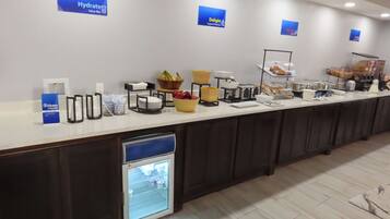 A buffet area with labeled sections for 'Hydrate Juice Bar' and 'Delight Yogurt & Pudding'. There are various food items and a refrigerator.