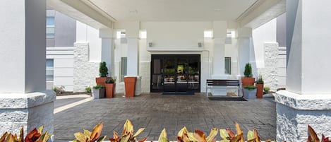 A covered outdoor area with a bench and potted plants.
