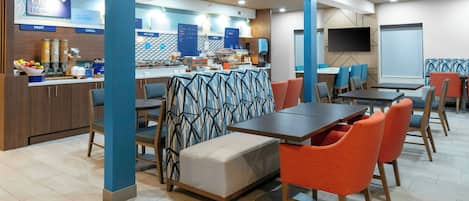 A modern dining area with a buffet, seating arrangements, and a television screen.