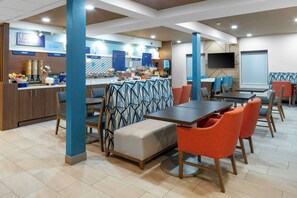 A modern dining area with a buffet, seating arrangements, and a television screen. - Holiday Inn Express & Suites Kimball by IHG (South Pittsburg)