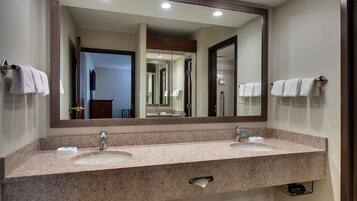 A bathroom with two sinks, a large mirror, and towels hanging on towel bars.