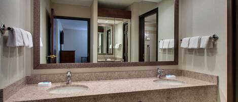 A bathroom with two sinks, a large mirror, and towels hanging on towel bars.