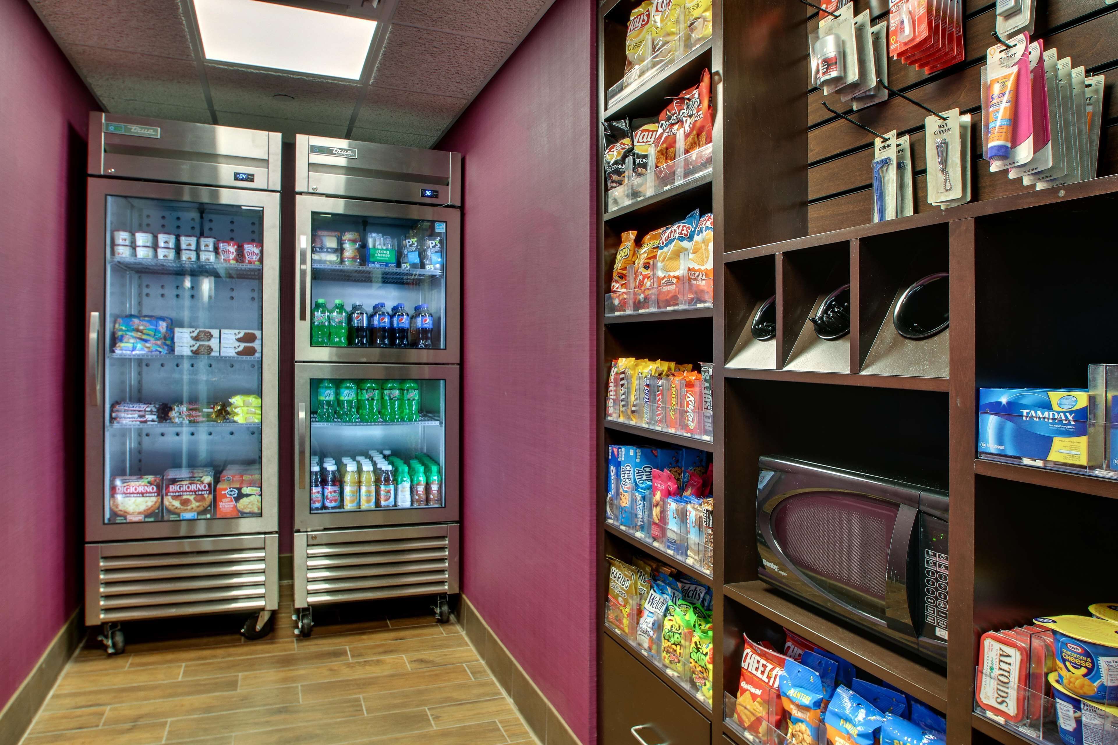 A corridor with two refrigerated display cases and shelves stocked with snacks and beverages.