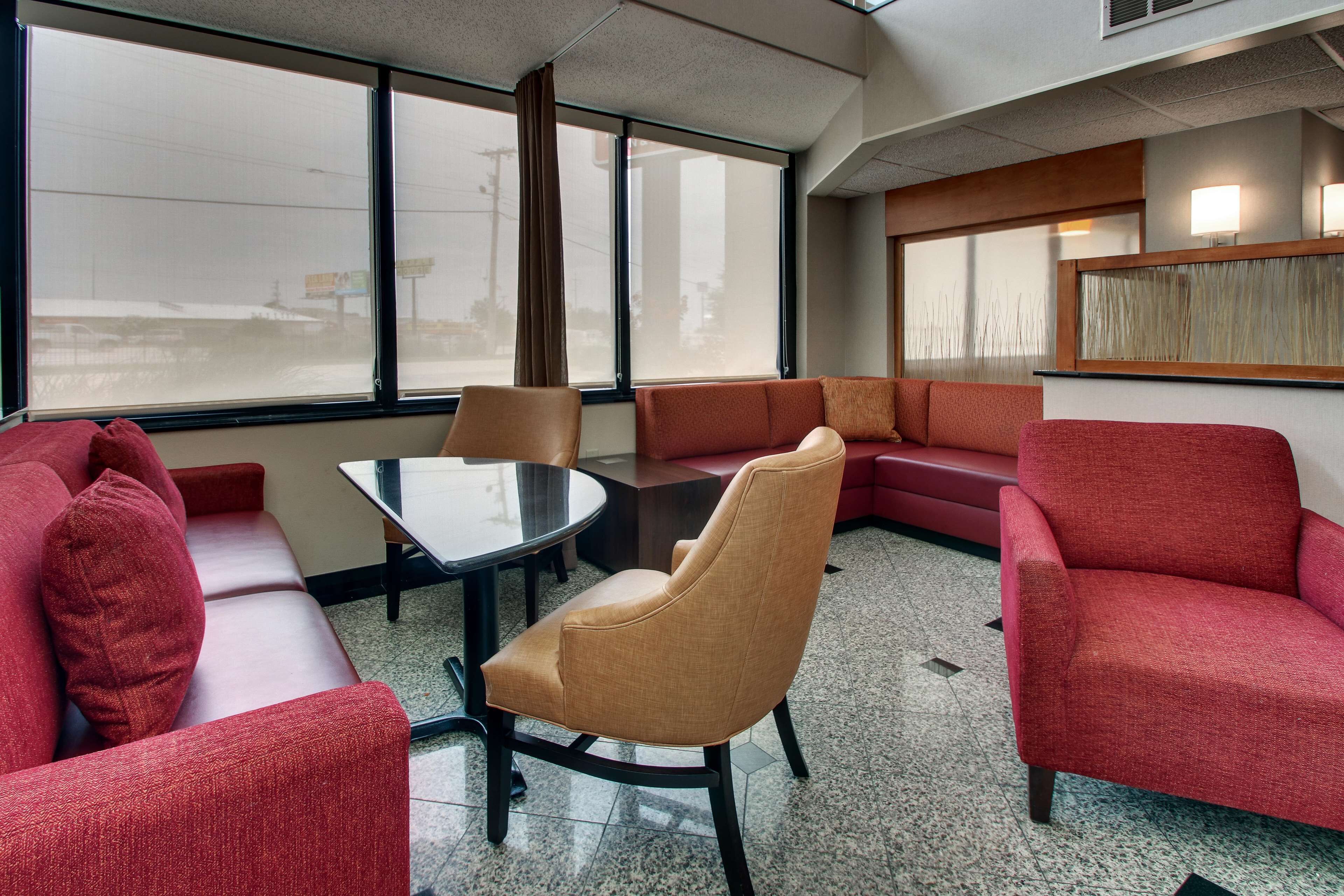 Eine Hotelhalle mit Sitzgelegenheit, einem runden Tisch und großen Fenstern.