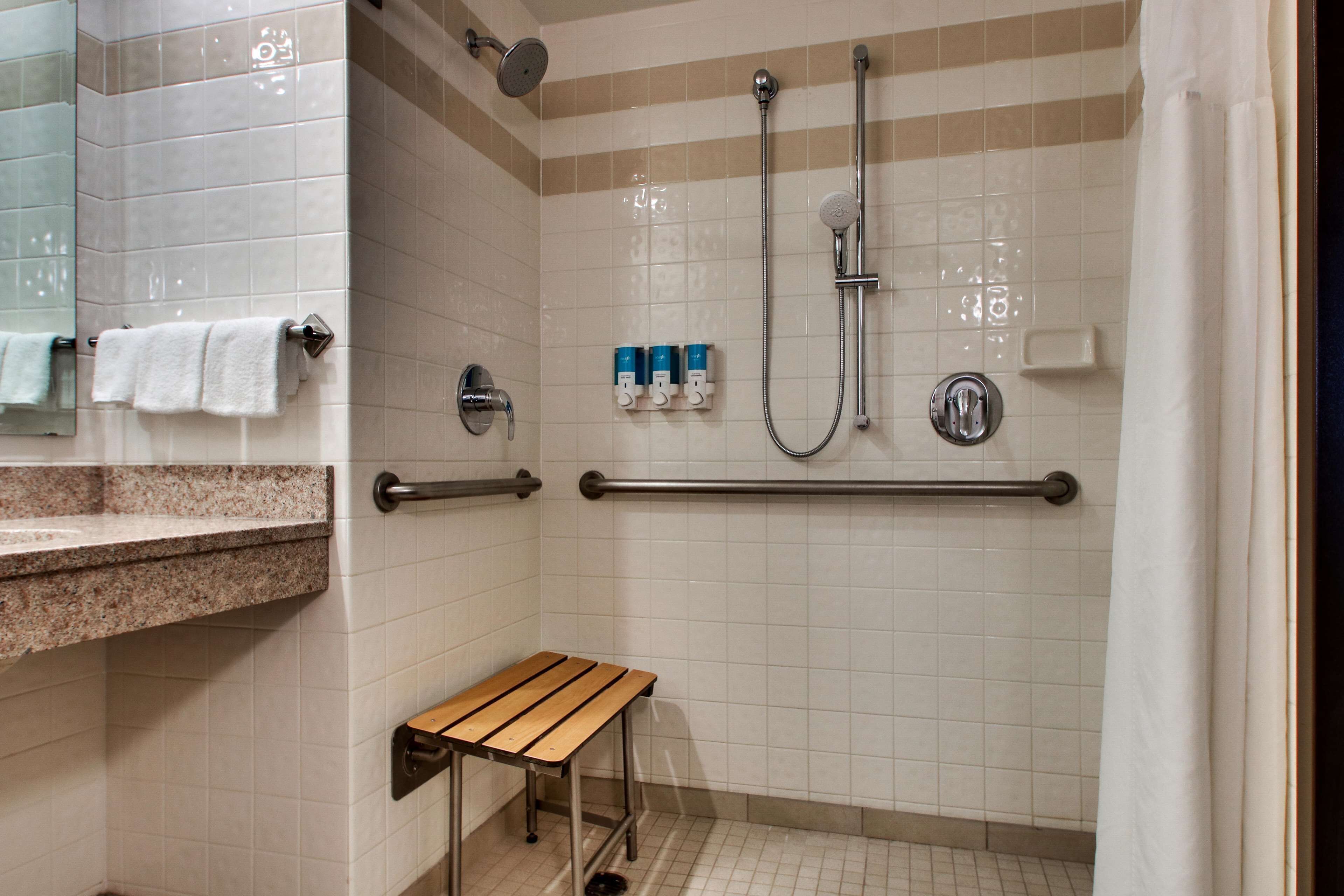 Un espace douche équipé d’un banc, de barres d’appui et d’un porte-serviettes.