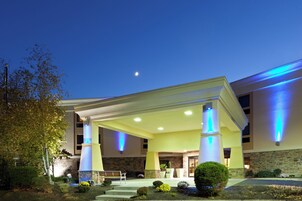 Un hotel con entrada cubierta, fachada de piedra y columnas iluminadas.