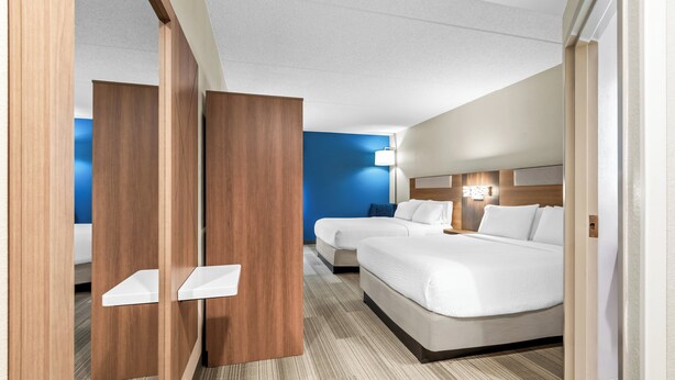 A hotel room with two beds, a blue accent wall, and a wooden partition. - Holiday Inn Express Hershey - Harrisburg Area by IHG (Hummelstown)