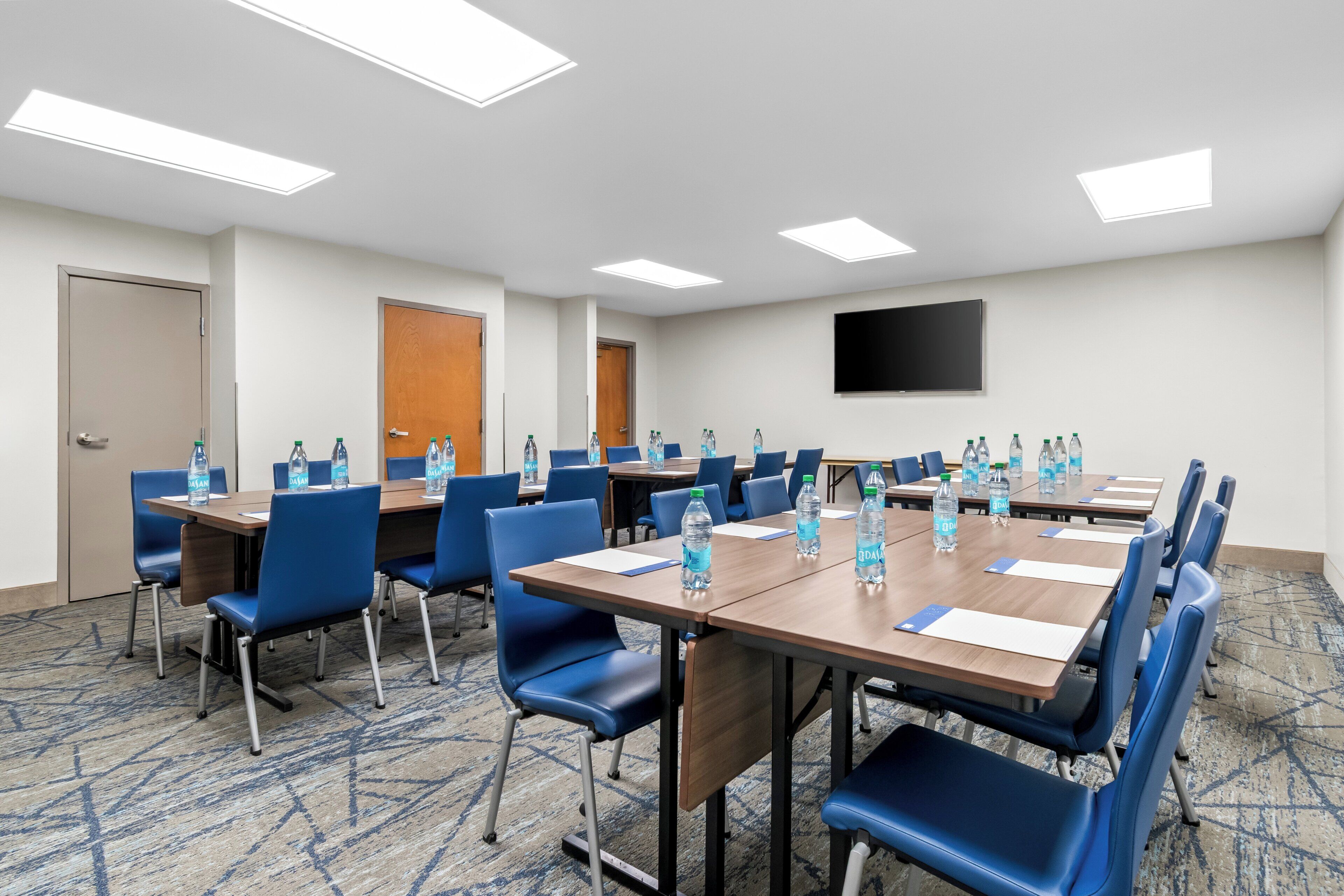 A conference room with multiple tables, chairs, and water bottles.