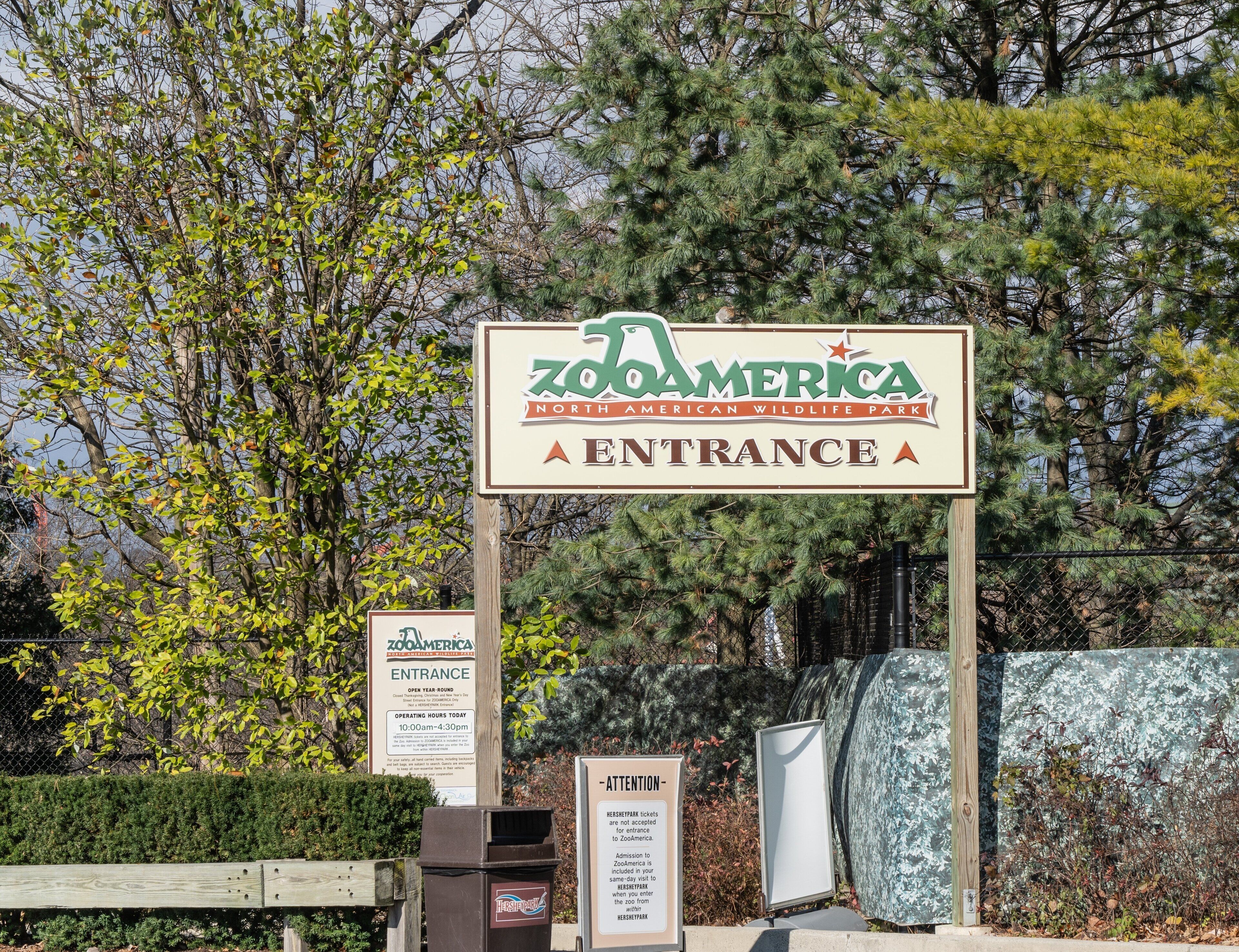 Señal de entrada al parque zoológico ZooAmerica North American Wildlife Park, con horarios de atención y aviso sobre restricciones de boletos.