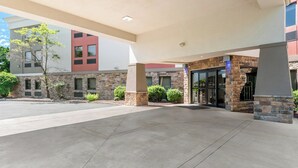 A building entrance with a stone facade, a covered walkway, and a parking lot. - Holiday Inn Express Hershey - Harrisburg Area by IHG (Hummelstown)