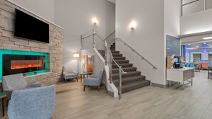 A modern interior with a staircase, a fireplace, and seating area. - Holiday Inn Express Hershey - Harrisburg Area by IHG (Hummelstown)