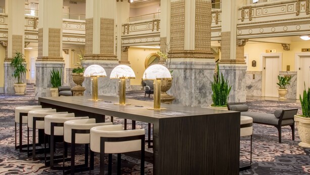 A reception area with a marble counter, bar stools, and potted plants. - Embassy Suites by Hilton Portland Downtown (Portland)