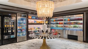 A hotel lobby with a central table, surrounded by refrigerated beverage dispensers and shelves stocked with snacks and beverages. - Embassy Suites by Hilton Portland Downtown (Portland)