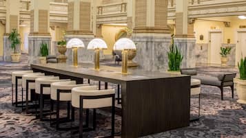 Un espace bar doté d’un comptoir en marbre, de tabourets de bar et de lampes décoratives.
