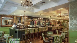 A bar area with multiple seating options, including bar stools and tables, and a bar counter with a cash register. - Embassy Suites by Hilton Portland Downtown (Portland)