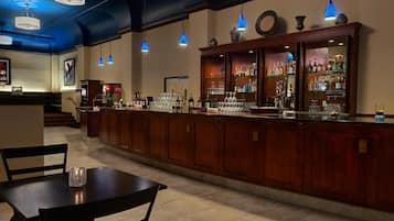 A bar area with wooden cabinets, a counter, and blue pendant lights.