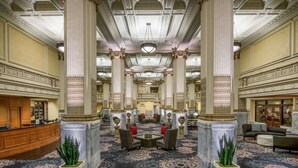 A grand lobby with high ceilings, ornate columns, and a central seating area with a patterned carpet. - Embassy Suites by Hilton Portland Downtown (Portland)
