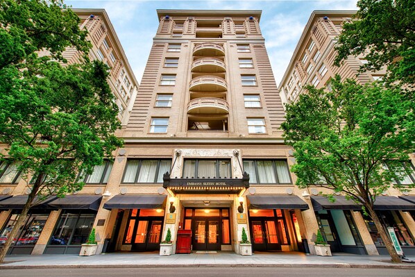 Experience the classic charm of Embassy Suites, featuring a symmetrical facade and central entrance, with multiple balconies and windows offering a range of room layouts and views.